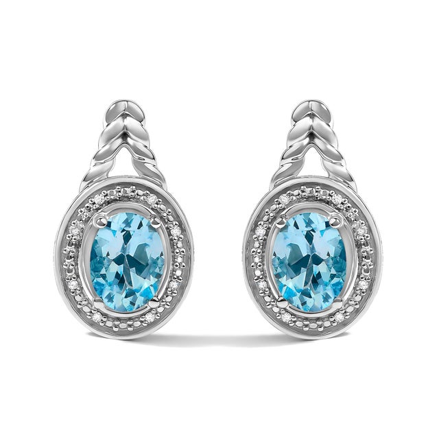 Immerse yourself in the sheer elegance of these sterling silver drop earrings, where the allure of natural oval blue topaz...