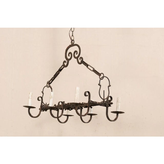 A French six-light iron chandelier from the mid 20th century. This vintage chandelier from France has an over-all...