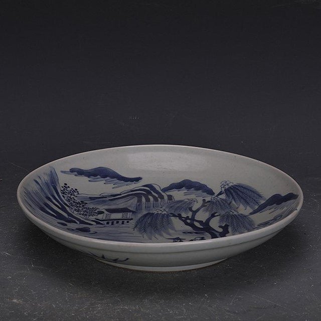 This finely hand-painted porcelain plate features a classic blue and white decoration, rendered in underglaze blue on a...