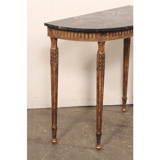 An Italian carved wood demi console, with original marble top, from the mid 20th century. This mid-century table from...