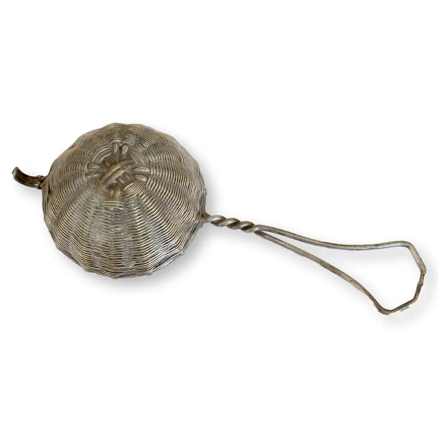 German silver-plate tea strainer. Made to sit over a mug or teacup, has a loop on front and the handle rests on the lip of...