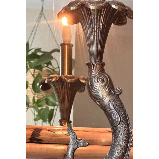 An elegant, sculptural table lamp crafted in bronze on a solid, veined black marble base. The composition features a...