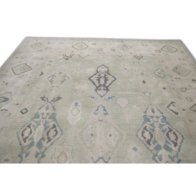 This modern Turkish Oushak rug is a stunning piece of art that has been handwoven using traditional techniques by skilled...