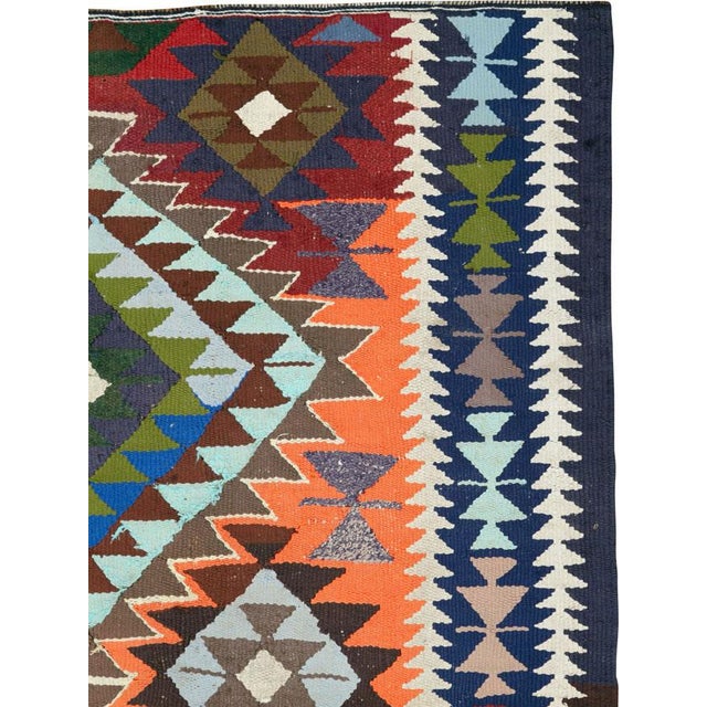 This Mid-20th century Persian flatweave kilim presents a bold, symmetrical composition centered on a series of stacked...