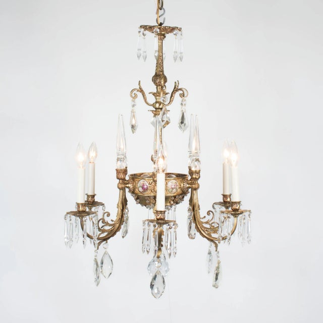 This early 20th-century six-arm Rococo-style gilt bronze and crystal chandelier features porcelain plaques inspired by the...