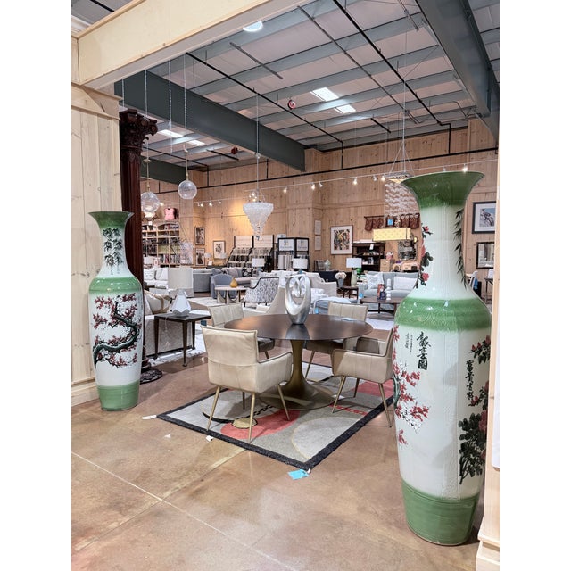 A striking pair of vintage Chinese floor-standing porcelain vases in a soft celadon green glaze, featuring elegant...