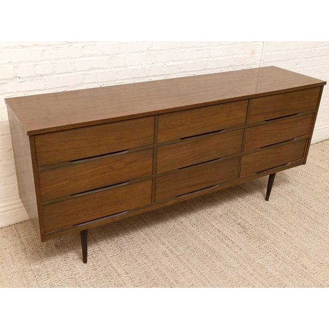A beautifully streamlined vintage dresser with a long, low silhouette and warm walnut finish. The nine-drawer layout gives...