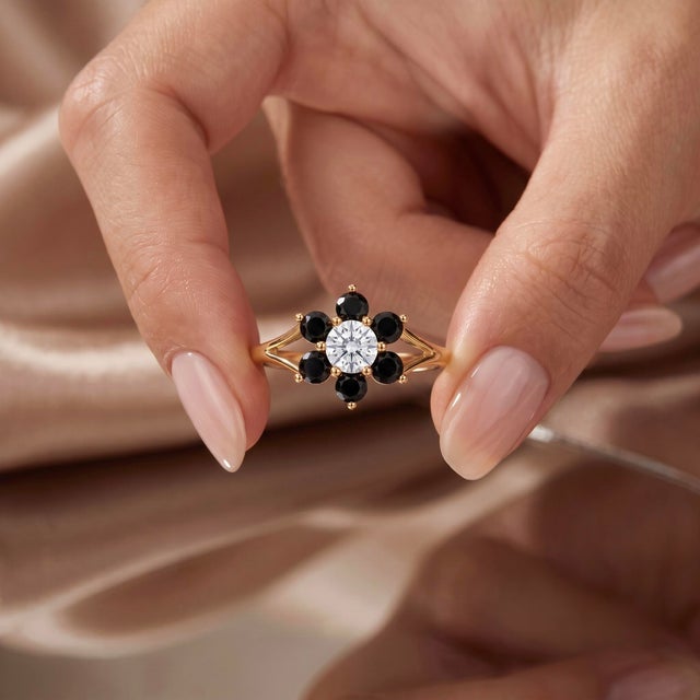 Bold and captivating, this flower-halo ring pairs striking midnight-black outer gems with a brilliant clear center,...