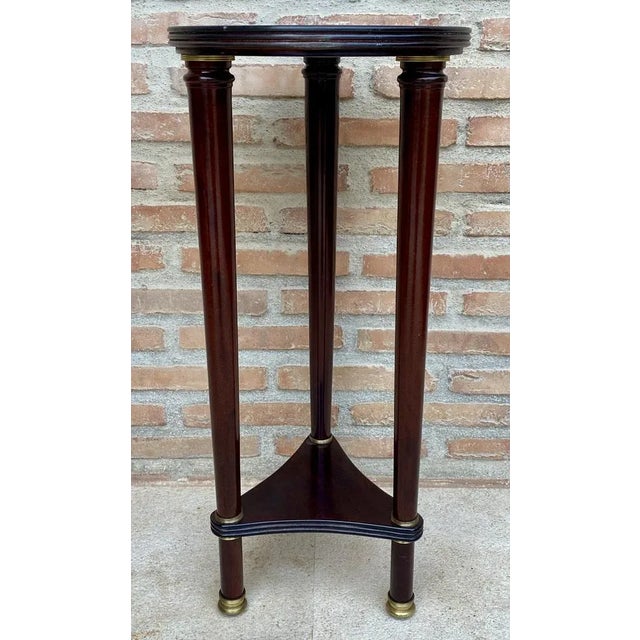 Vintage French style pedestal table. Made of wood with a triangular base that supports turned columns and a round wooden top.