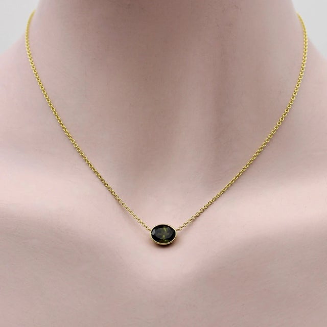 A dark green bezel set tourmaline creates the perfect palate for a simple necklace. Suspended in the middle of a 14k gold...