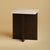 The Tinos is a Roman travertine and oak nightstand, a small, low table scaled for the side of a bed. Stone and timber are...