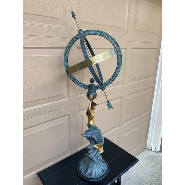 A beautifully crafted armillary sphere featuring a mermaid and dolphin, evoking the timeless elegance of coastal or Palm...