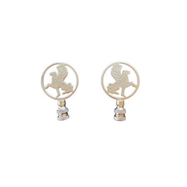 A striking pair of vintage brass finials featuring mirrored winged gryphons (griffins) within circular frames. Each finial...