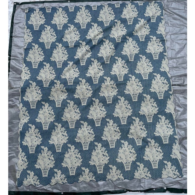 A single vintage woven cotton coverlet featuring blue and white floral basket decoration against a geometric background...