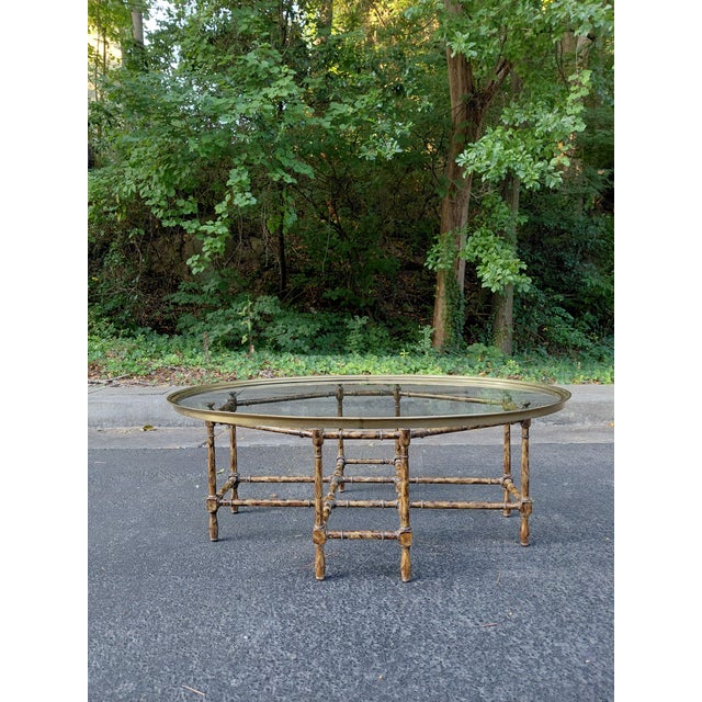 A stylish vintage oval coffee table inspired by classic faux bamboo designs, featuring a sculptural resin base with an...