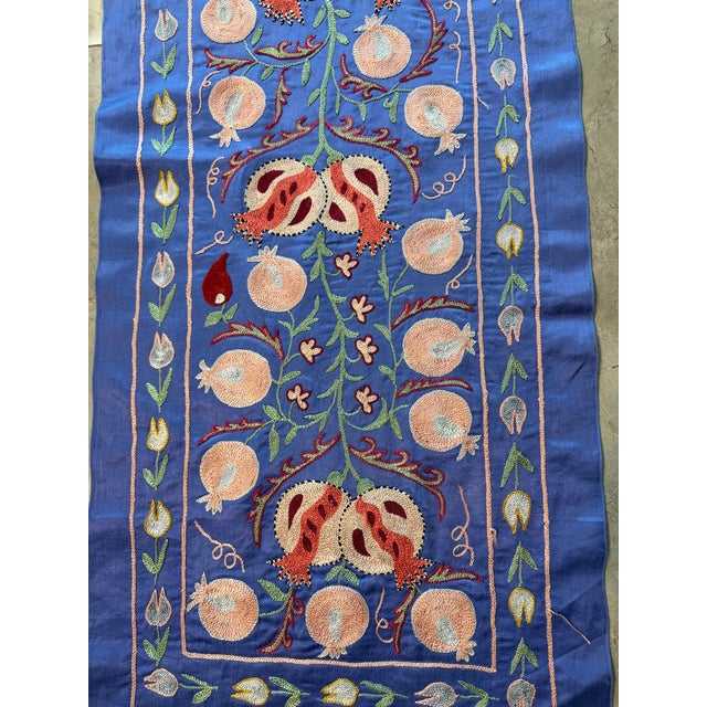 Hand-embroidered Suzani table runner from Uzbekistan — peach pomegranates and crimson tulip blossoms on a periwinkle blue...