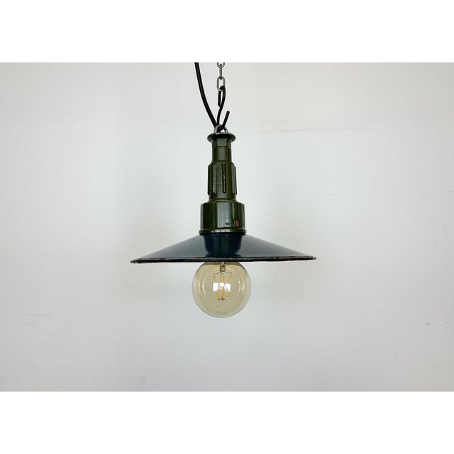 Industrial blue enamel pendant light made in Poland during the 1960s. White enamel inside the shade. Green cast aluminium...