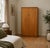 A 1960s mid-century double wardrobe in warm teak veneer, featuring clean lines, wooden handles and subtle segmented...