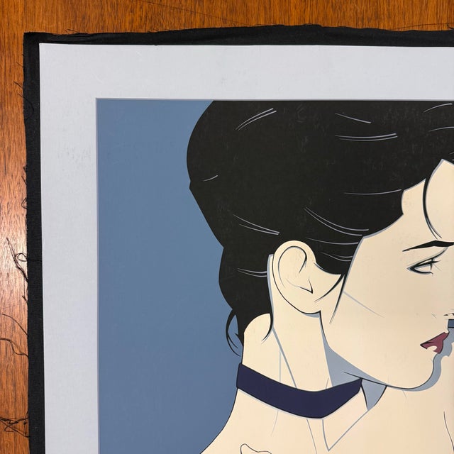 This serigraph by Patrick Nagel titled “Commemorative #6” or depicts a woman in an Art Deco and Pop Art style with a...