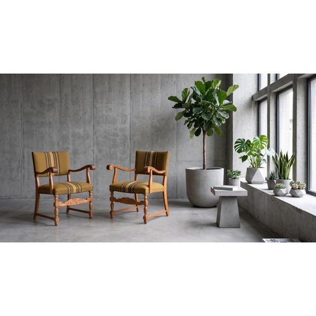 Pair of armchairs in solid oak, produced in Denmark during the 1960s. The design features finely carved details and a...