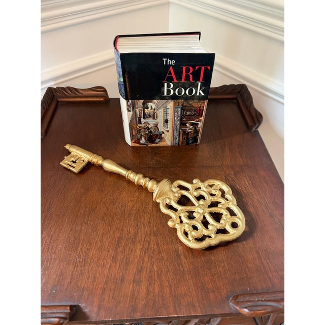 Oversized vintage decorative skeleton key sculpture crafted in cast iron and later finished in gold paint. Featuring an...