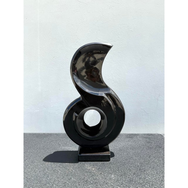 A bold sculptural stone piece defined by fluid movement and architectural form, this abstract composition features a...