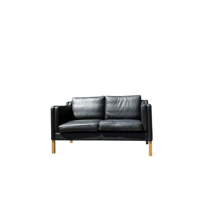 Upholstered in supple black leather with minimal natural wear, this piece delivers both durability and timeless appeal....