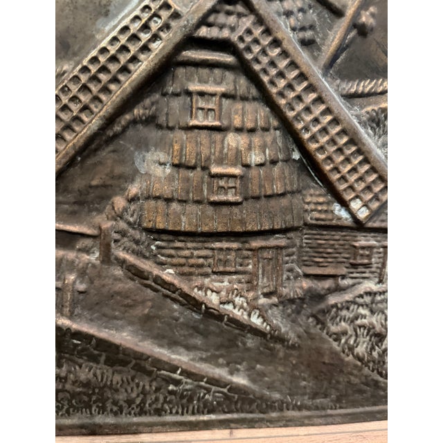 Antique stamped metal fireplace summer cover with a raised windmill landscape, cottage, bridge and birds, inside a molded...