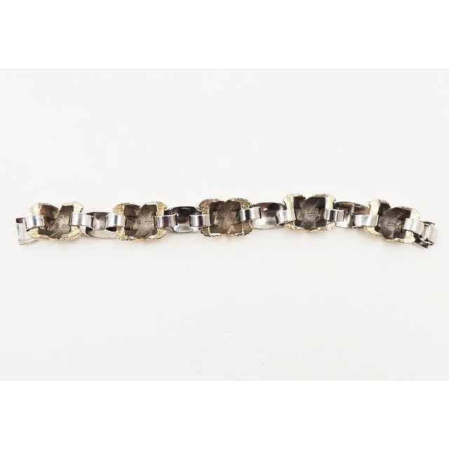 This is part of Chairish’s Costume Jewelry assortment. 1970s rhodium plated with textured goldtone x connectors bracelet...