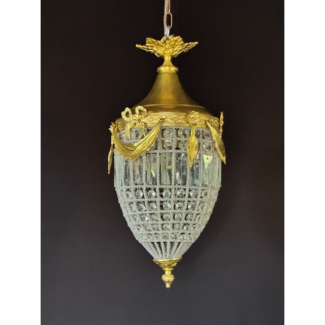 A refined 1970 French Louis XVI style bronze and crystal lantern chandelier, made in Europe and designed with a warm gold...