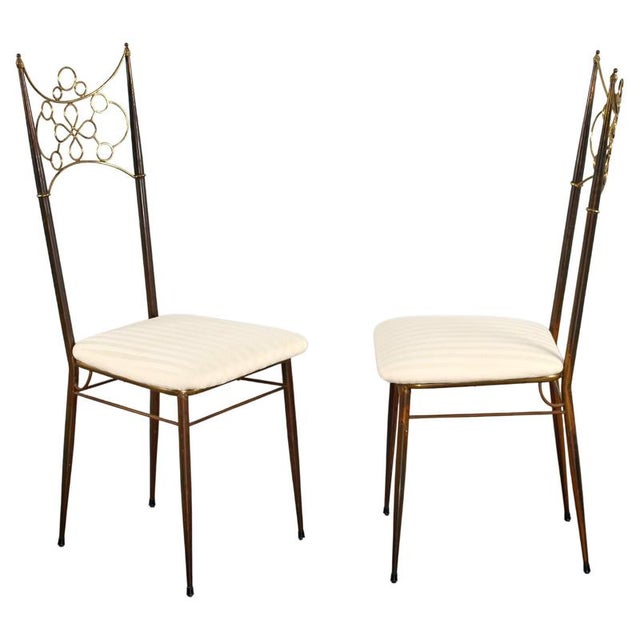 A pair of high-backed chairs crafted from metal and brass, with a white, banded seat. Made in Italy in the 1950s. Wear...