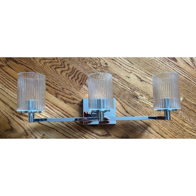 Visual Comfort's Generation Lighting Lando Three Light Bath Vanity Sconce. Width: 24.625" - Height: 7.75" Backplate:...