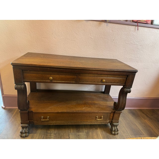 Antique carved oak or wood console/buffet table featuring decorative scrolled legs, claw feet, and open bottom shelving.