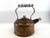 Antique copper tea kettle featuring a beautifully aged surface with natural verdigris and warm tonal variation. The form...