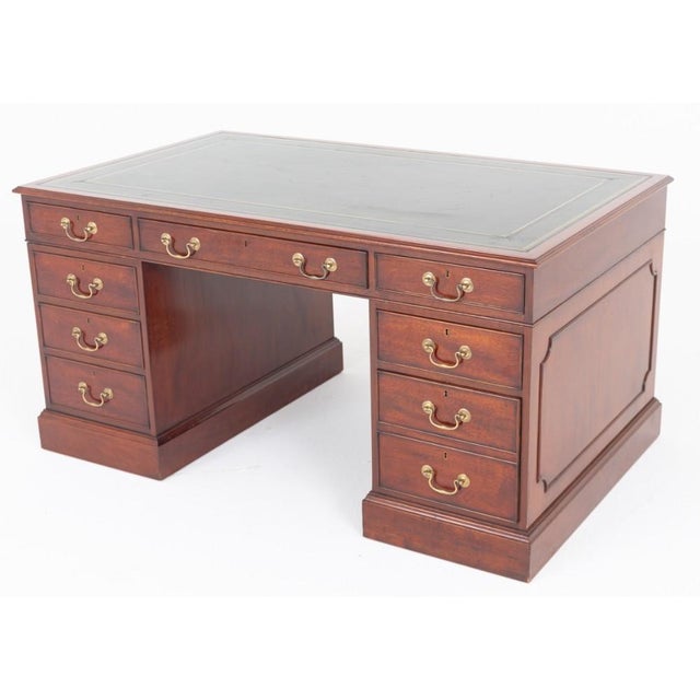 A fine Georgian Revival partners desk, crafted in rich mahogany and raised on a substantial plinth base The desk features...