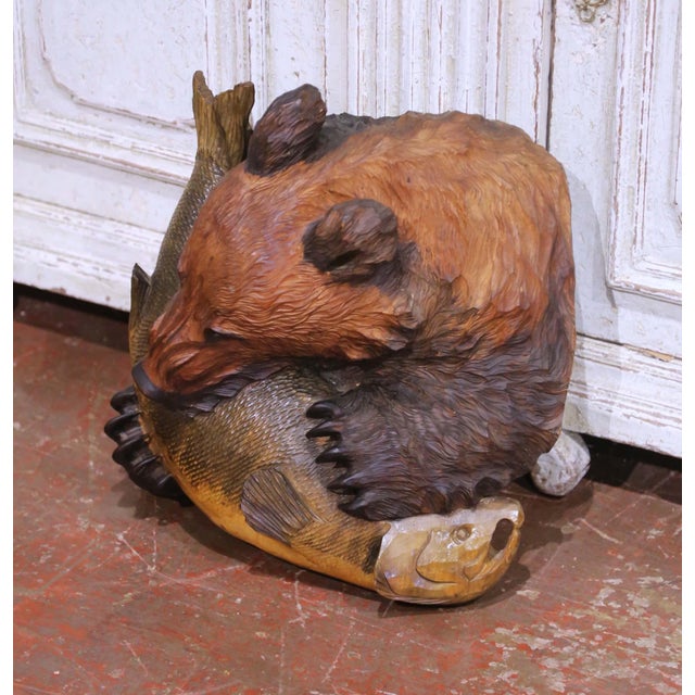 This striking antique Black Forest carved wall sculpture depicts a powerful bear clutching a freshly caught fish, rendered...
