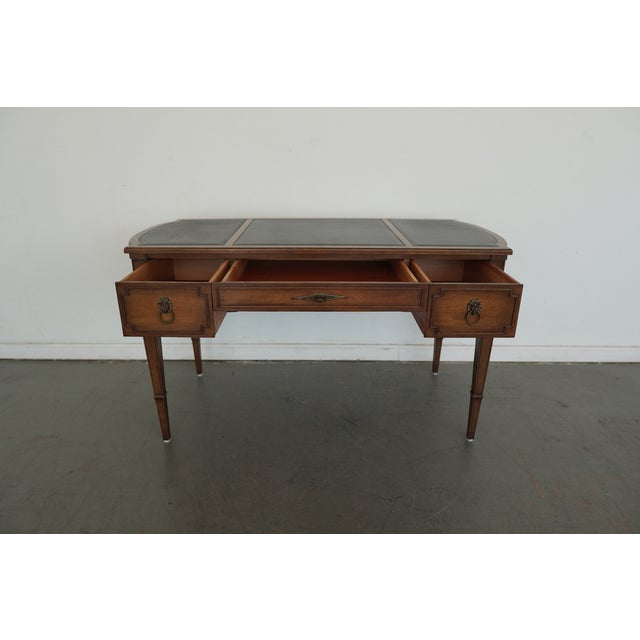 This exquisite writing desk, likely crafted by Baker Furniture, captures the refined neoclassical sensibility that defined...