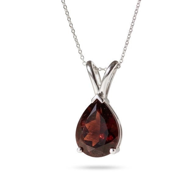 This elegant pendant necklace features a captivating Garnet gemstone, celebrated for its deep wine-red hue and rich,...