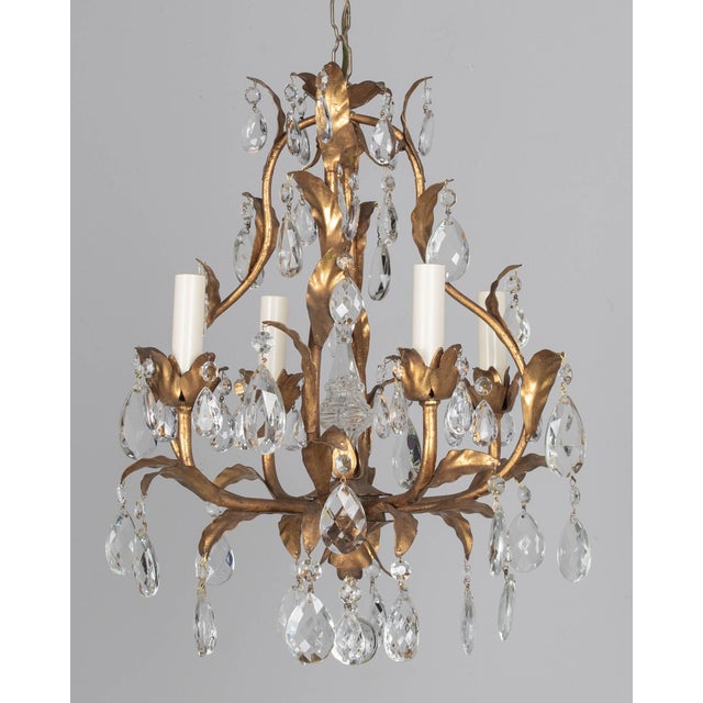 An Italian Hollywood Regency style four-light gilt metal chandelier with tôle leaves and crystal prisms. Brass canopy and...