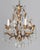 An Italian Hollywood Regency style four-light gilt metal chandelier with tôle leaves and crystal prisms. Brass canopy and...