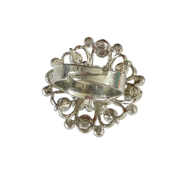 Beautifully crafted vintage ring featuring a striking round silhouette adorned with shimmering faux diamond accents. The...