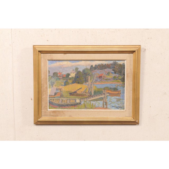 A Swedish waterfront country village painting, in gilt frame, from the mid 20th century. This charming mid-century...