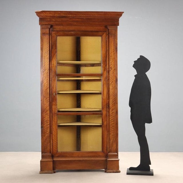 Baroque walnut corner cabinet. Tripartite door with glass panels, column uprights, interior with five shelves. Italy, 18th...