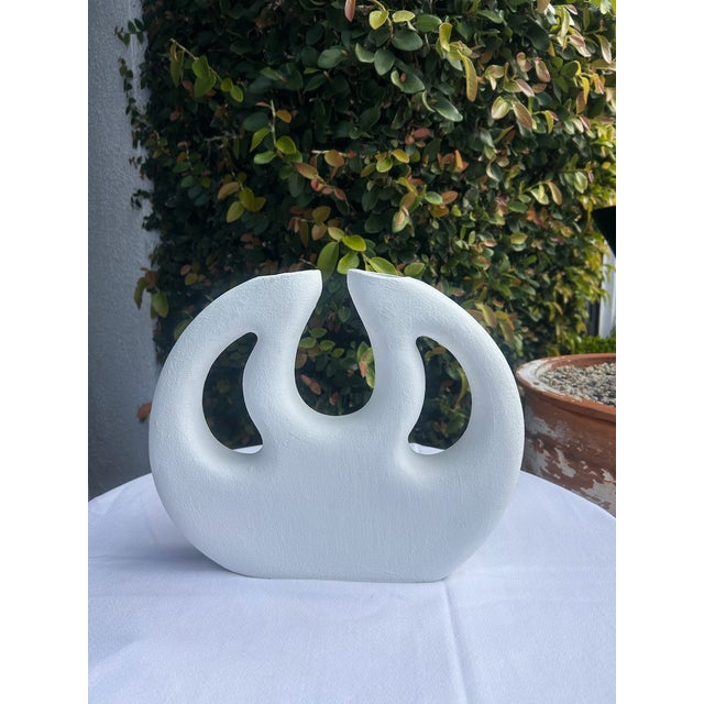 Vintage matte white pottery vase featuring a sculptural abstract form with dual angled openings. The organic curved...