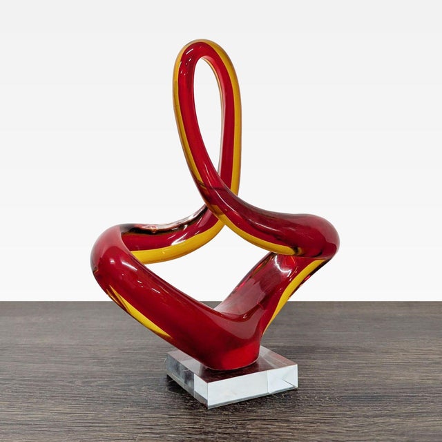This unique sculpture features an elegant twisted design in rich red and amber glass. It stands on a clear square base for...