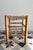 A charming antique low stool with a rustic feel, featuring a honey-yellow wooden frame and a beautiful woven straw seat....