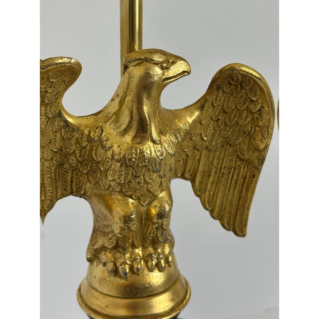 A Federal style eagle table lamp produced in the United States during the 1950s, combining gilt metal, brass, and turned...
