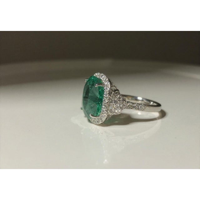 A show-stopping 18K white gold cocktail ring centered on a magnificent 10.20 carat natural oval emerald, surrounded by 66...
