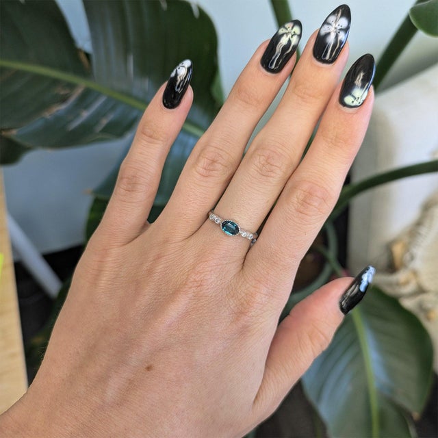 An indicolite tourmaline in a deep ocean blue anchors this solid 14K white gold ring, accented by four earth-mined...