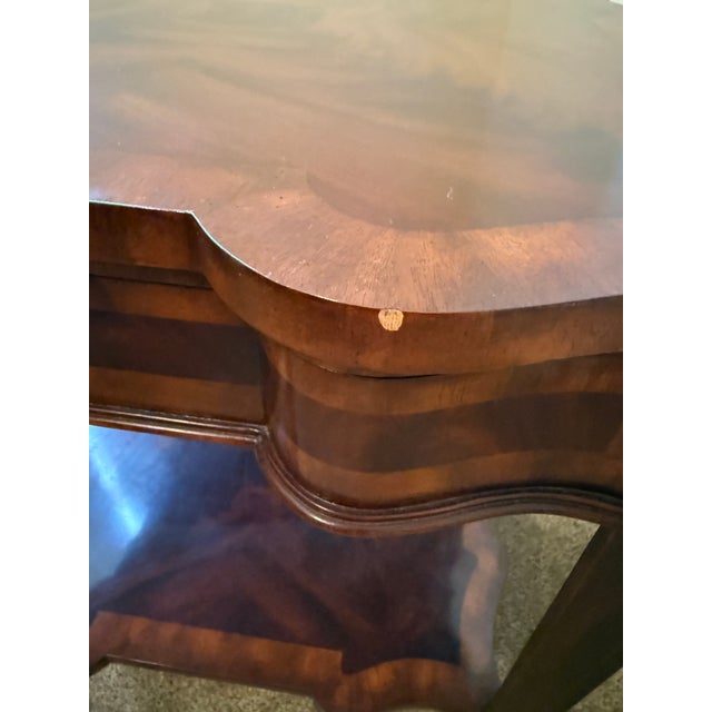 A beautifully crafted Maitland-Smith occasional table featuring a shaped serpentine top in flame mahogany veneer,...